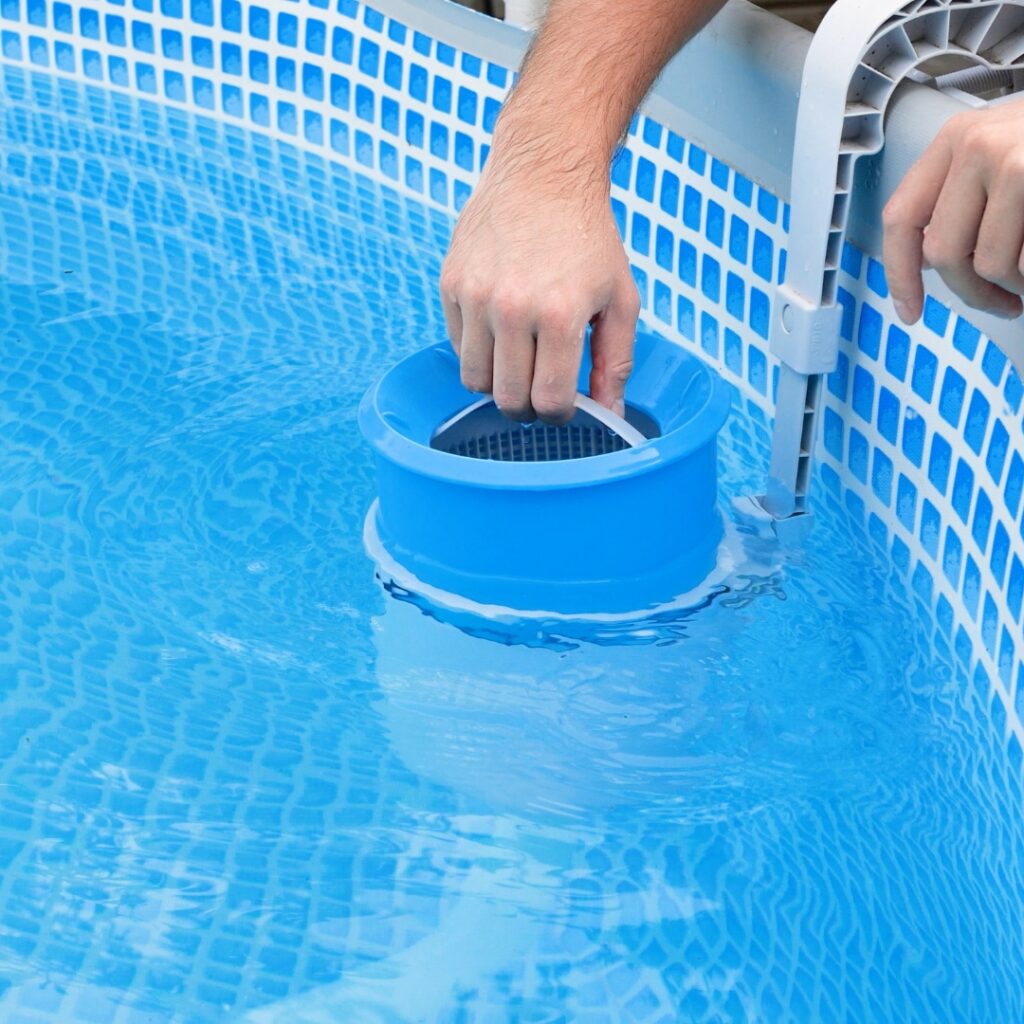 man cleaning water filter in pool